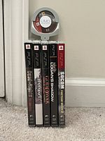 Six PSP game cases vertically aligned and one loose UMD disc visible on top.