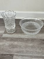 Photo showing clear crystal vase with scalloped edges and decorative cut pattern, standing next to a clear diamond cut crystal bowl.