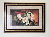 Full view of the framed floral wall decor showing magnolia flowers with dark wood and gold accented frame and matting.