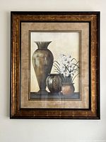Full view of the framed wall art showing three brown vases and floral arrangement with brown frame and beige mat