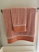 Orange and white chevron patterned bath towel and hand towel hanging on a silver towel bar