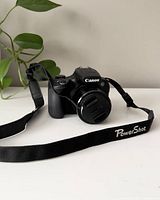 Front view of Canon PowerShot SX60 HS with lens cap on and PowerShot strap attached