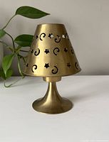Vintage brass tea light holder with celestial cut-out patterns including stars and crescent moons, shown assembled
