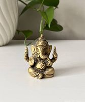 Front view of the small brass Ganesha figure, showing detailed face, headdress, and hand gestures.