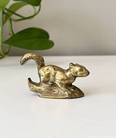 Side view of the brass squirrel figurine showing the form and patina.