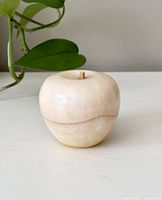 Front angle view of vintage marble apple showing the smooth beige polished marble surface with natural veins and small stem.