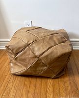 Full view of the vintage pleather foot rest showing rectangular shape and patchwork stitched design on brown pleather material