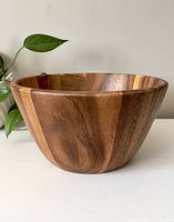 Front side view of a large, round wooden mixing bowl showing its natural wood grain and smooth finish.