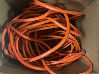 Box containing long orange extension cord coiled inside.