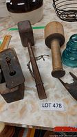 Photo showing wooden mallet, metal and wood hand plane, green glass insulator, and metal wire basket on table.