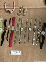 Lot of assorted wristwatches displayed on tan surface, showing variety of bands and dial styles.