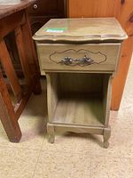 Front view of the wooden bedside table showing drawer with metal handle and open lower storage space.