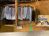 Wicker basket holding multiple CDs in jewel cases arranged in two sections, with a loose Golden Age of Country album beside it.