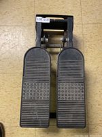 Top view showing the dual textured foot pedals and compact design of the black exercise stepper.