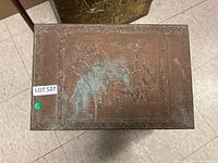 Top view showing embossed horse and rider design on the lid with wear and patina.