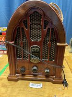 Front view of a GE antique style radio with wooden arched cabinet, cloth speaker grille, and three knobs.