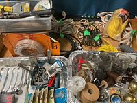 Photo showing assorted hand tools, wrenches, alligator clips, wires, small hardware jars, and packaged rope.