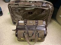 Photo showing two luggage pieces, a larger suitcase with protective cover and a smaller travel bag in front