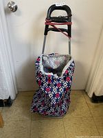 Full view of the foldable shopping cart buggy showing metal frame, floral fabric bag, and handle with bungee cord.