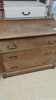 Photo showing front view of vintage solid wood dresser with four drawers and metal handles.