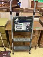 Full view of the Cosco Signature folding step stool with two steps, showing its metal frame, handle, and black plastic steps.