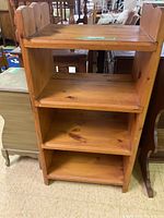 Full view of the wooden bookcase showing shelves, scalloped sides, and natural wood finish