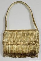Front full view of the rectangular evening bag showing the golden beaded fringe and silky fabric base with beaded handle.