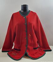 Front view of the red GEIGER sweater on a mannequin showing button closure, pockets, and trim.