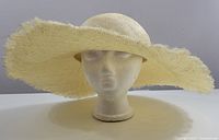 Front view of the wide brim sun hat showing frayed edges and rounded crown on a mannequin head.