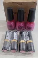 Three bottles of Sinful Colours nail polish in pink shade #2195 and four Revlon lipsticks in black tubes with gold bands wrapped in plastic, all new.