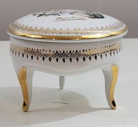 Side view of the trinket box on three curved legs with gold accents.