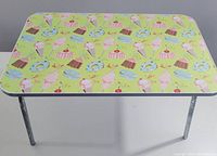 Front view of the vintage-style breakfast in bed table with metal legs and patterned dessert-themed top.