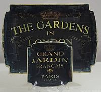 Large and small decorative serving platters with vintage garden and city text designs displayed together.