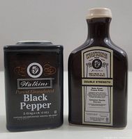 Front view of Watkins black pepper salt shaker and vanilla extract bottle pepper shaker showing labels and design.