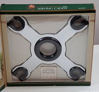 Front view of unused Napa Essentials wine serving caddy in original packaging showing the caddy design holding four wine glasses bases and a complimentary food and wine pairing guide.