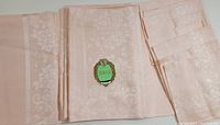 Folded peach damask tablecloth with original superior damask label attached, showing floral woven pattern and fabric texture.