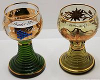 Front angle showing both Roemer crystal goblets with green ridged bases, hand-painted gold leaf decorations, and inscriptions.