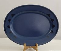 Full view of the large oval platter showing the navy blue surface and black triangle detail around the rim.