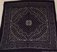 Top-down photo of square vintage purple table accent showing detailed white floral and geometric pattern and fabric texture.