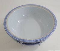 Overhead front angle view of larger porcelain bowl showing blue geometric border on rim, white interior, and footed base.