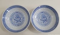 Top view of two blue and white porcelain sauce bowls showing dragon designs and border patterns.