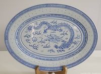 Oval porcelain platter showing the blue dragon and cloud design, with geometric patterned borders on white porcelain.