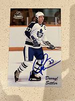 Signed Darryl Sittler photo showing him in Toronto Maple Leafs vintage uniform skating on ice, signed in bold blue marker.
