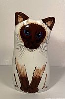 Front view of vintage ceramic cat vase by Nina Lyman, showing detailed painted face and paws of Siamese cat with blue eyes.