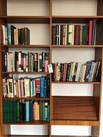 Two full shots of the bookshelf with multiple rows of English and Arabic books.