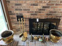 Overview photo of brass planters and fireplace tools set in front of brick fireplace