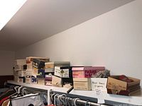 Multiple shoe boxes of various brands and sizes on a shelf.