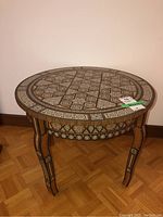 Full front view of round table showing geometric inlay top, apron, and legs