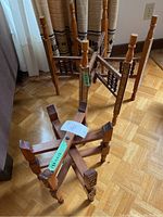 Two vintage folding tray table bases of different sizes standing on a hardwood floor next to curtains, showing overall shape and condition.