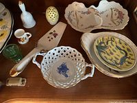 Various small decorative dishes, cups, ladle, and basket with floral patterns on wooden display shelf.